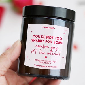 May include: A black glass candle jar with a white label that reads "You're not too shabby for some random guy off the internet." The label also includes the text "Happy Valentine's Day! Love, Millie x" and "Handpoured in Manchester."