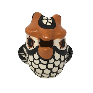 May include: A ceramic owl figurine with black and white scales and orange accents. The owl has a round body and large eyes.