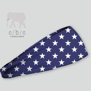 Könnte beinhalten: Ein blaues Stirnband mit einem Muster aus weißen Sternen. Das Stirnband besteht aus einem weichen, dehnbaren Material. Das Logo c/b/c colorband creative befindet sich in der oberen linken Ecke.