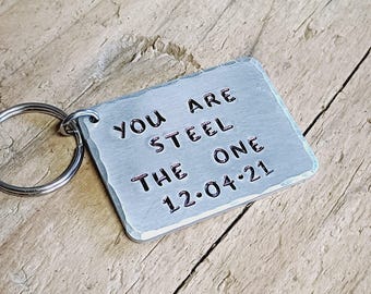 May include: A silver keychain with a rectangular tag that reads "You are steel the one 12.04.21".