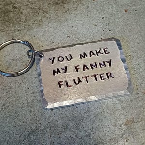 May include: A silver keychain with a hammered metal tag that reads "You make my fanny flutter".