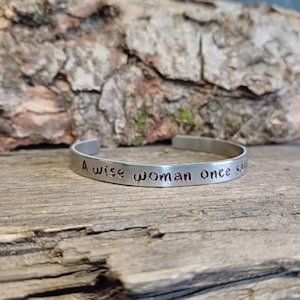 May include: A silver bracelet with the inscription "A wise woman once said..." in copper lettering.
