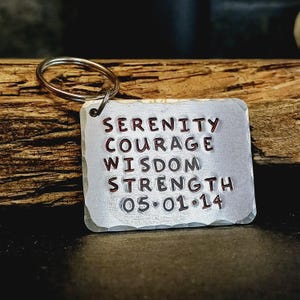 Può includere: Portachiavi in metallo argentato con un'etichetta rettangolare su cui è scritto "Serenity Courage Wisdom Strength 05.01.14".
