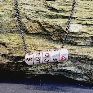 Könnte beinhalten: Eine silberne Halskette mit einem Anhänger, auf dem in einem kreisförmigen Design "GOOD TIMES" steht. Der Anhänger besteht aus einzelnen Perlen mit einem kleinen roten Herzen am Ende.