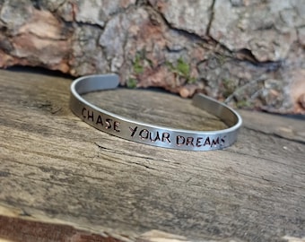 May include: Silver bracelet with the words "Chase Your Dreams" engraved in copper.
