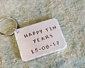 May include: A silver keychain with a rectangular tag that reads "Happy Tin Years 15.08.17".