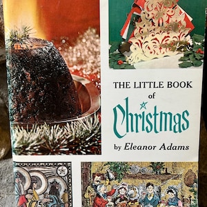 May include: A vintage book cover featuring a Christmas theme. The cover includes the title "The Little Book of Christmas" by Eleanor Adams, with illustrations of a Christmas tree, a cake, and a family scene. The text "AMY VANDERBILT SUCCESS PROGRAM FOR WOMEN" is also visible.