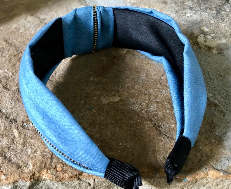 K&ouml;nnte beinhalten: Ein blaues Denim-Haarband mit Rei&szlig;verschlussdetail und schwarzem Gummiband auf der R&uuml;ckseite.