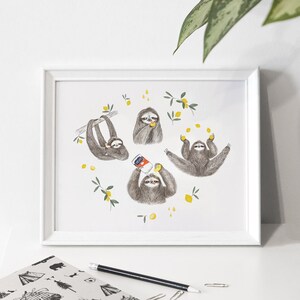 Peut inclure: Une impression encadrée blanche avec une illustration aquarelle de quatre paresseux. Les paresseux sont entourés de citrons jaunes et de feuilles vertes. Un paresseux tient une canette de jus, un autre jongle avec des citrons et les deux autres mangent des citrons.