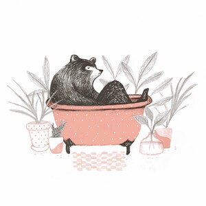 Puede incluir: Un oso negro sentado en una ba&ntilde;era rosa con lunares blancos. La ba&ntilde;era tiene patas negras y est&aacute; rodeada de plantas en macetas.