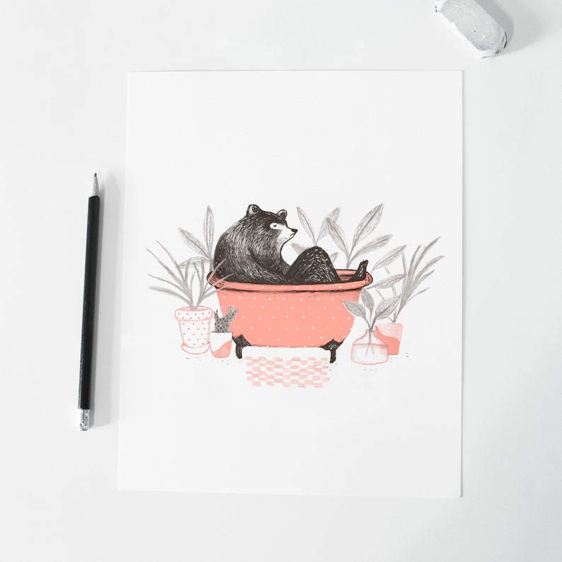 Puede incluir: Un oso negro sentado en una ba&ntilde;era rosa con lunares blancos. El oso est&aacute; rodeado de plantas verdes en macetas.