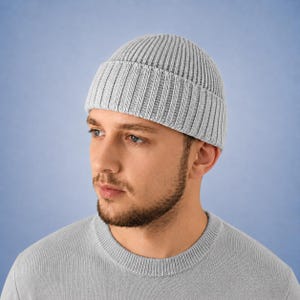 May include: A light gray ribbed knit beanie with a folded cuff. The hat features a vertical textured pattern throughout the fabric, providing a consistent look from the crown down to the brim. The material appears soft and woven in a classic style.