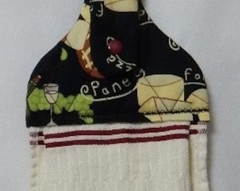 May include: A black and white kitchen towel with a red stripe design. The towel has a hanging loop with a black and white fabric featuring a wine and grapes design. The fabric reads "Pane e Vino" and "For the Love of Wine".