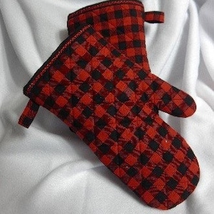 May include: Red and black checkered oven mitt with a quilted design. The mitt has a loop for hanging.