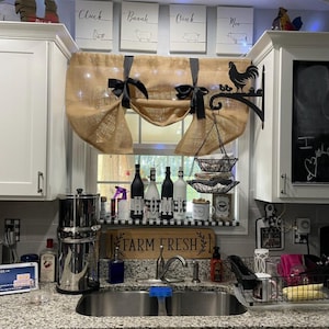 May include: A kitchen sink with a farmhouse style decor. The sink is made of stainless steel and has a single bowl. The countertop is made of granite and has a black and white checkered pattern. There is a wooden sign that says "Farm Fresh" above the sink. There are also several bottles of wine on the counter.
