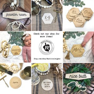 May include: A collection of wooden signs with various sayings, including "powder room", "K+B June 15, 2023", "Two Months", "One Year", "One Month", "Madeline", "cheers", "Sit Your Glass Down", "nice butt", and "Madeline Lee". The signs are made of natural wood and have a rustic, farmhouse style.