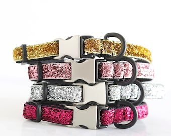 May include: Four sparkly dog collars in gold, pink, silver, and red. The collars are stacked on top of each other and have silver buckles.