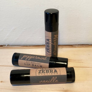 May include: Three black lip balm tubes with brown paper labels. The labels have the text "Rustic Zebra Boutique" and the flavors "peppermint", "vanilla", and "strawberry".