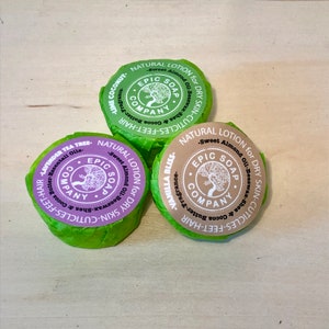 May include: Three round natural lotion bars from Epic Soap Company, wrapped in green paper. The labels feature text and a tree logo. Scents include Lime Coconut, Vanilla Bliss, and Lavender Tea Tree.