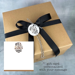 May include: A brown gift box with a black ribbon and a white tag that says "Life is better with a dog". A white gift card with the same text is included. The gift card can be personalized with a message.