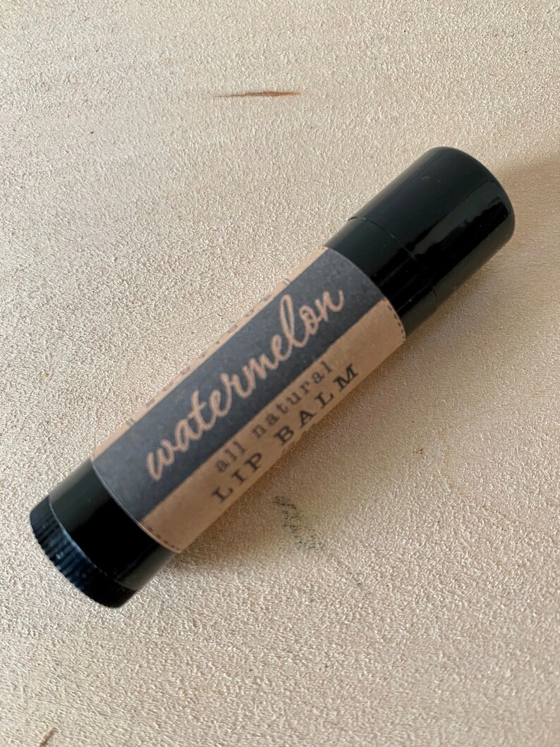 May include: A black lip balm tube with a brown paper label that says "watermelon all natural LIP BALM".