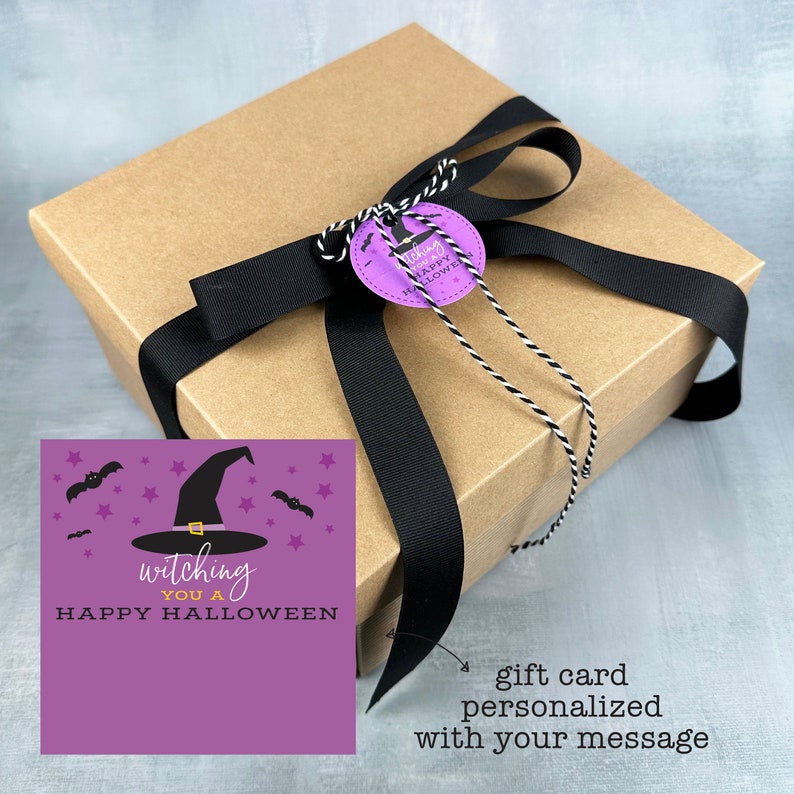 May include: A brown gift box tied with a black ribbon and a decorative tag. The tag is purple with the words "witching you a HAPPY HALLOWEEN" and a witch hat graphic. A gift card with the same theme is included.