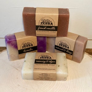 May include: Four bars of handmade soap with brown paper labels. The labels have the text "Rustic Zebra Boutique" and the scent of each soap: French Vanilla, Lavender, Oatmeal & Honey, and Rosemary & Thyme.