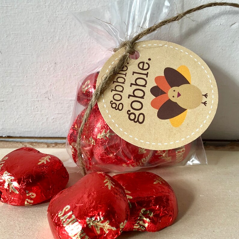 May include: A clear cellophane bag tied with twine, containing heart-shaped candies wrapped in red foil. A round tag with the words "gobble. gobble." and a turkey illustration is attached.
