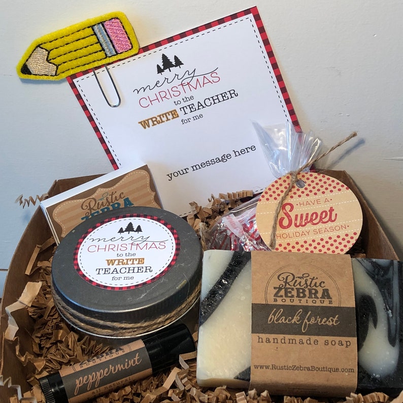 May include: A Christmas gift basket for a teacher with a black and white soap bar, a candle, a peppermint lip balm, a small bag of candy, and a card that says "Merry Christmas to the Write Teacher for me".