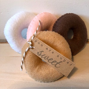 May include: Three felt donuts in white, pink, and brown with a brown paper tag that says "You are super sweet".