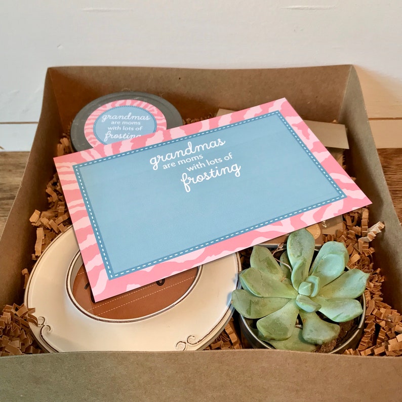 May include: A gift box filled with a small succulent plant, a white ceramic plate, and a card with the text "Grandmas are moms with lots of frosting".