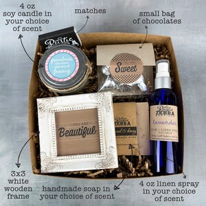 May include: A gift box filled with a 4 oz soy candle, a small bag of chocolates, a 3x3 white wooden frame, a bar of handmade soap, and a 4 oz linen spray. The box is filled with shredded paper and the items are arranged neatly. The candle is labeled "grandmas are moms with lots of frosting". The chocolates are labeled "You are Sweet". The frame is labeled "You are Beautiful". The soap is labeled "Rustic Zebra Boutique Real & Honey Handmade Soap". The linen spray is labeled "Rustic Zebra Boutique Lavender 100ml Linen Spray 4 oz | 120ml Shake well before each use".