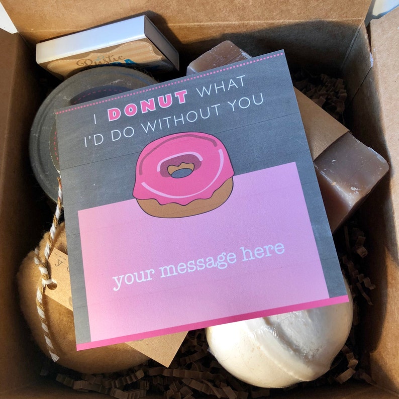 May include: A gift box filled with various items, including a bath bomb, soap, a jar of something, and a card that says "I donut what I'd do without you." The card has a pink and brown donut illustration and a space for a message.