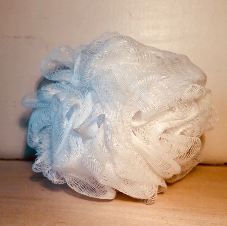 Puede incluir: Un puff de ba&ntilde;o blanco hecho de un material suave de malla. El puff est&aacute; arrugado y parece nuevo.