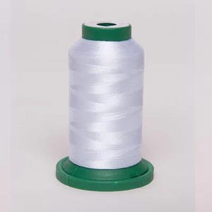 May include: A spool of white thread with a green plastic bobbin. The thread is wound tightly and has a smooth, shiny finish.