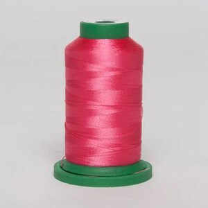 May include: A spool of pink thread with a green plastic bobbin.