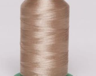 May include: A spool of tan-colored thread with a green base and top. The thread is tightly wound, showing a slight sheen. The spool is centered against a plain white background, highlighting the thread's texture and color.