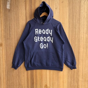 May include: A navy blue hooded sweatshirt with the words "Ready Steady Go!" printed in white on the front.