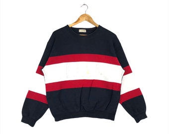 May include: A navy blue, red, and white striped sweatshirt with a white logo on the front. The sweatshirt has long sleeves and a crew neck.