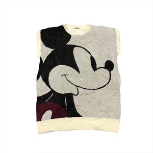 Puede incluir: Una camiseta sin mangas gris claro y blanca con un gran gráfico de Mickey Mouse. El diseño incluye elementos negros, grises y burdeos. La camiseta tiene cuello redondo y dobladillo blanco.