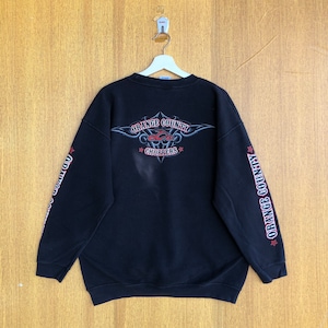 以下が含まれることがあります： 赤と白の「ORANGE COUNTY CHOPPERS」の文字が入った黒いスウェットシャツ。袖にも同じ文字が入っています。スウェットシャツの背面には、「ORANGE COUNTY CHOPPERS」の文字が入ったグラフィックデザインがあります。