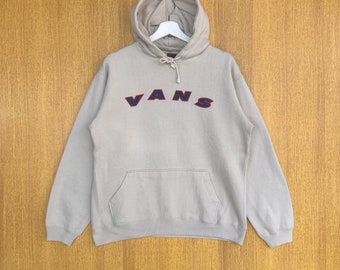May include: A beige hooded sweatshirt with a navy blue and red "VANS" logo on the front.