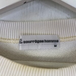 May include: A white sweatshirt with a white tag that reads "Courr&egrave;ges Homme" and "M" in black text.