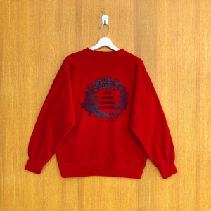 May include: Red sweatshirt with a black and white graphic print of a floral design with the text "Shorebreak Surf" and "Go for the Sunset, the Sunrise, the Ocean of Endless Waves".