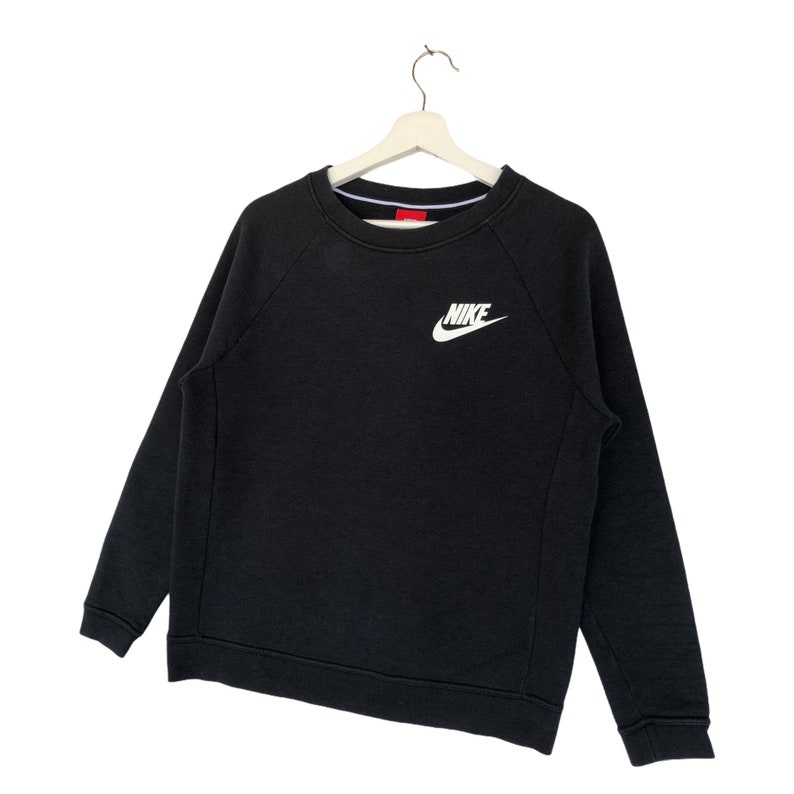 May include: Black Nike sweatshirt with a white Nike logo on the front. The sweatshirt has a crew neck and long sleeves.