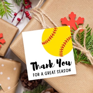 Puede incluir: Etiqueta de regalo blanca con una pelota de softball amarilla con costuras rojas. La etiqueta tiene texto negro que dice "Gracias por una gran temporada".