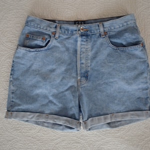 May include: Light blue denim shorts with a cuffed hem. The shorts have a button fly and five pockets.