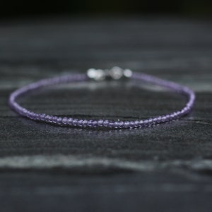 Può includere: Un delicato braccialetto di perline di ametista con una chiusura in argento. Il braccialetto è fatto di piccole perline rotonde ed è di colore viola chiaro.