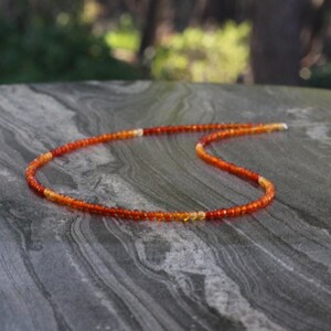 Puede incluir: Un collar delicado hecho de peque&ntilde;as cuentas redondas de cornalina en tonos naranja y rojo. Las cuentas est&aacute;n enhebradas en una fina cadena de plata.
