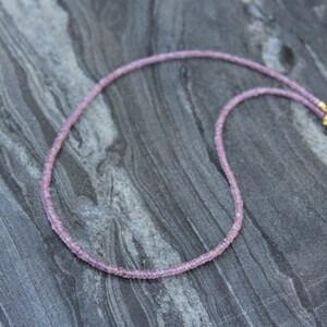 May include: A delicate pink gemstone necklace with a gold clasp. The necklace is made of small, round beads and is approximately 18 inches long.